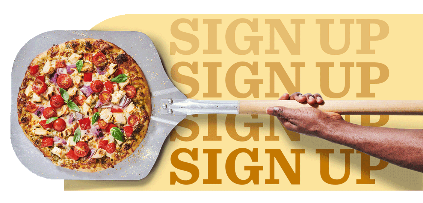 Overhead view of pizza on a pizza peel with cheese, grilled diced chicken, cherry tomatoes, onions and basil