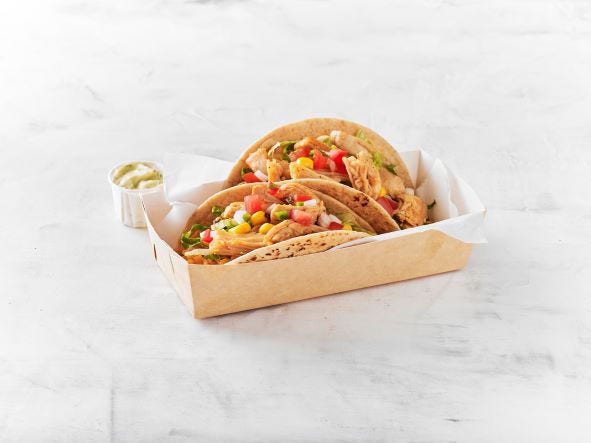 Cardboard plated two al pastor chicken tacos with corn, pico and sauce on the side
