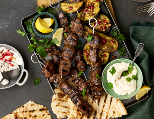 Grilled pomegranate steak tip kebabs paired with grilled flatbread, za'atar roasted eggplant, whipped garlic toum