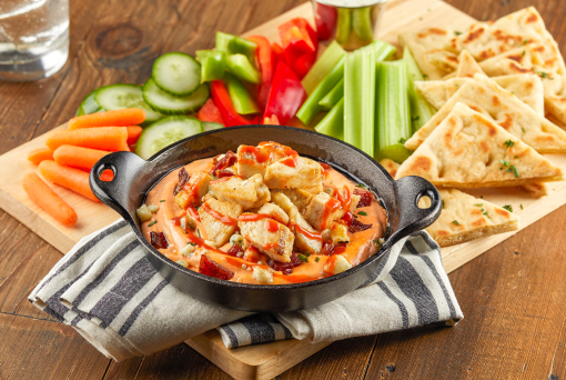 A bowl of buffalo cheese dip featuring bacon and chicken.
