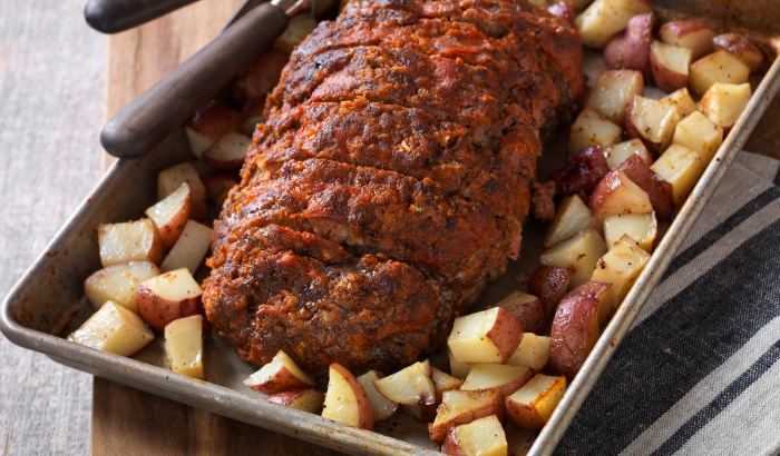 Sliced meatloaf glazed with a light tomato sauce and served with roasted red potatoes on a sheet pan