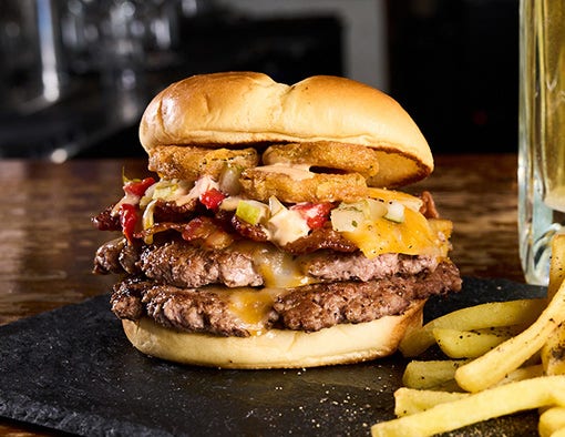 Double cheeseburger with bacon, cheese, pickle de gallo, fried pickles, and ranch on a brioche bun