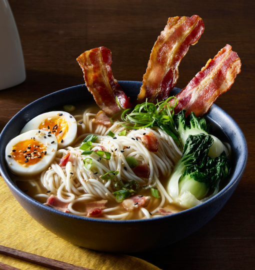 Bowl of ramen with crispy bacon, soft-boiled egg, baby bok choy, and scallions