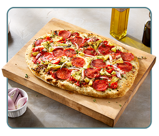 A pepperoni flatbread pizza on a cutting board with oil and vinegar