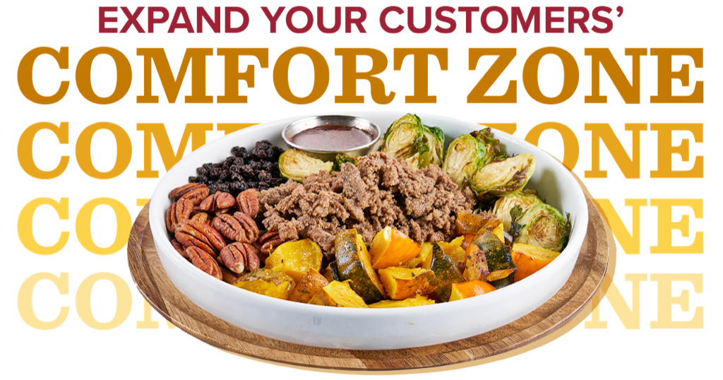 A bowl loaded with sliced beef, acorn squash, pecans, black currants, Brussels sprouts and sauce in a metal ramekin
