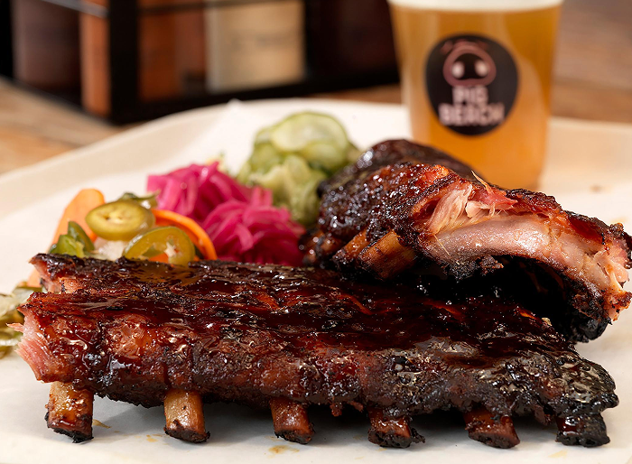 Glazed BBQ ribs with caramelized exterior, served with pickled cucumbers, jalapeños, and red cabbage