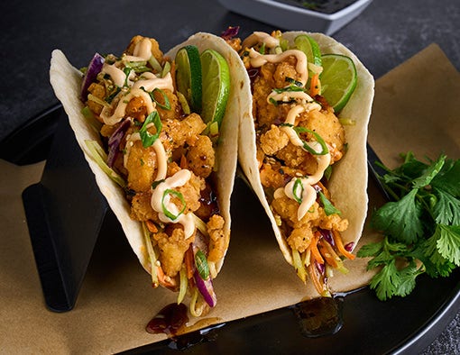 Crispy chicken bites in tortillas with Asian slaw, soy ginger sauce, and wonton chips on the side