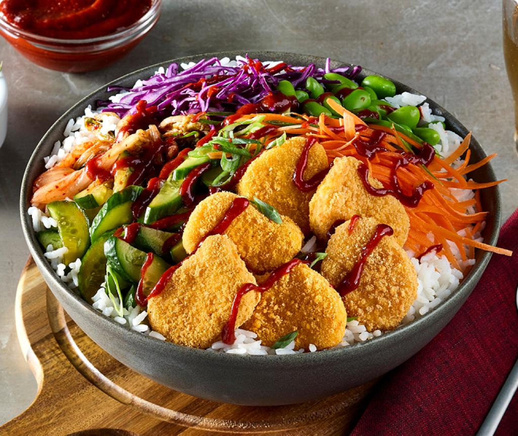 Bowl of sticky rice topped with kimchi, pickled cucumber, gluten-free chicken nuggets, and a fried egg