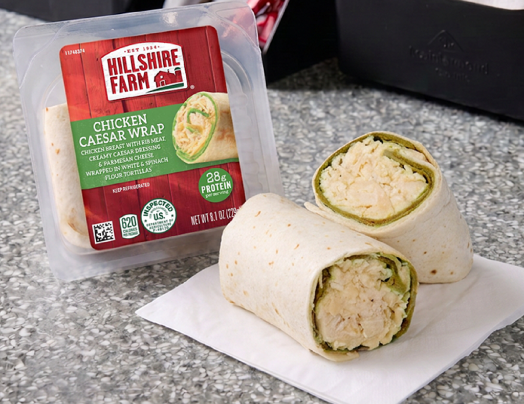 Two chicken Caesar wraps, one in a rigid sandwich pack and the other setting on a napkin