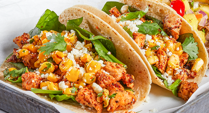 grilled chicken tacos garnished with street-corn style toppings and fresh herbs