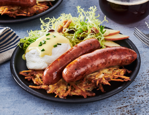 Brunch with sausages, poached eggs on latkes, and salad on a blue-gray table