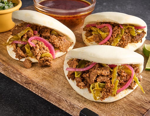 Bao buns filled with seasoned beef, pickled red onions, and jalapenos, served with dipping broth