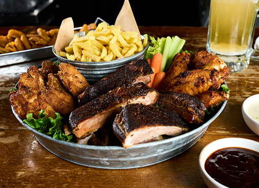ultimate bbq plater with ribs and wings and a side of fires and BBQ sauce