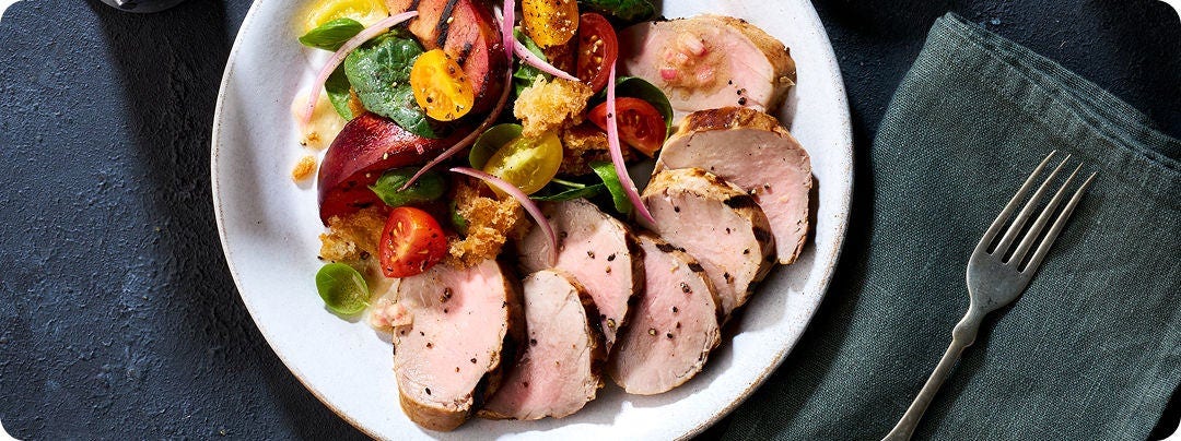 Pork loin with a side salad on a white plate