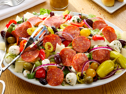 Antipasto salad topped with pepperoni, olives, onions and more