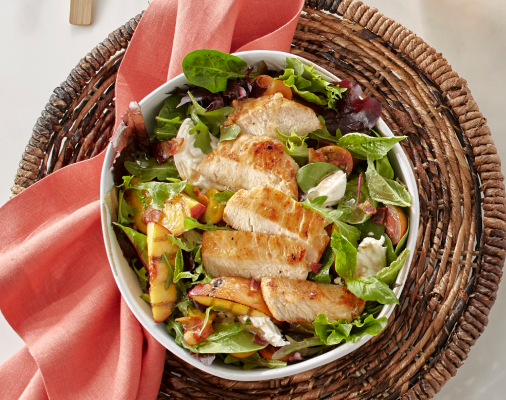 Grilled chicken breast slices served over mixed greens with tomatoes, grilled peaches and soft cheese