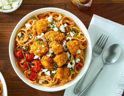 spicy honey chicken breast chunks dance with creamy tomato sauce and tangy feta on a stage of tender linguine