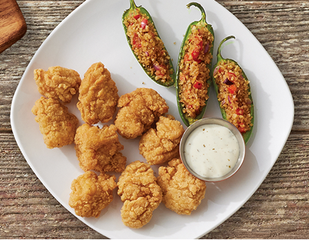 Chicken breast chunks with a side of stuffed jalapenos and sauce