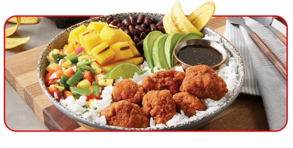 Bowl with crispy chicken chunks, dices mixed vegetables, black beans, pineapple chunks, plantains and slice avocado on a bed of white rice