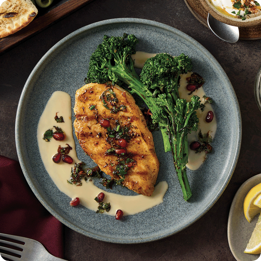 grilled chicken breast, broccolini and a cream sauce artistically spread on the plate