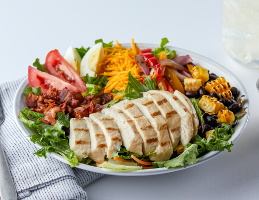 Southwest Grilled Chicken Salad topped with hard-boiled egg, black beans, corn and bell peppers