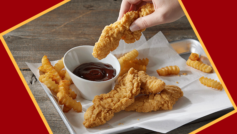 Chicken strips being dunked in sauce