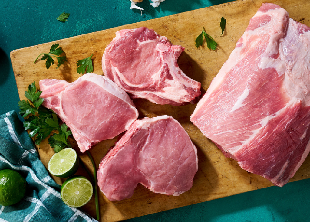 Raw pork loin on a butting board with limes