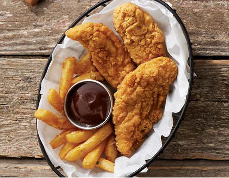 Chicken tenders in a basket with a side of frech fries and sauce