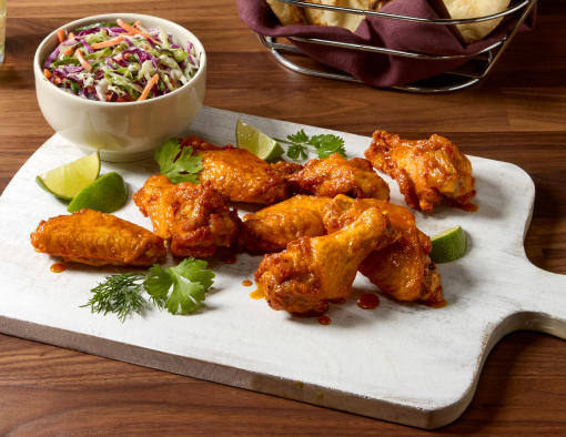 Hot Honey Vindaloo Wings on a white plate with a side of slaw