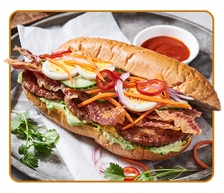 hoagie roll filled with sausage patties, bacon, hard-boiled egg slices and shredded vegetables