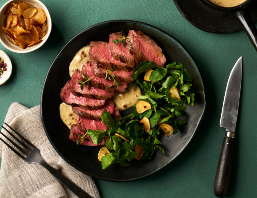 Grilled flat iron steak served with Sichuan au poivre sauce, fresh watercress and crispy garlic chips