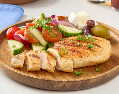 Sliced grilled chicken breast served with cucumber tomato salad, red onion, olives and feta cheese
