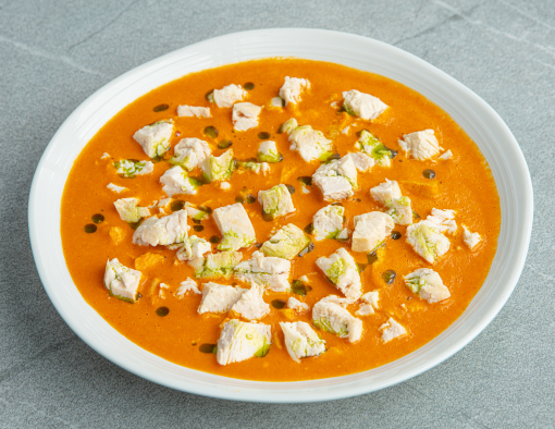 Large bowl of creamy red pepper bisque with bits of diced chicken breast meat