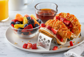 Breakfast pancake chicken tacos with a side of fruit and syrup