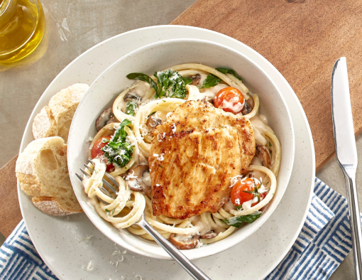Chicken breast filet placed on a bed of tender bucatini pasta