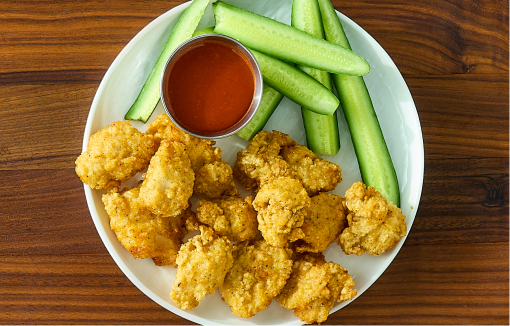 Plate of chicken breast chunks with zucchini sticks and sauce.