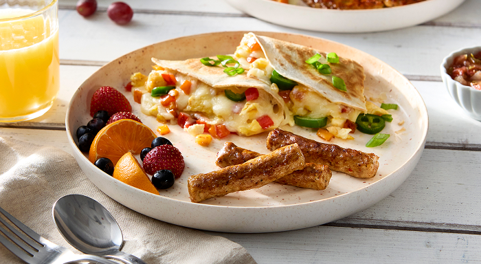 A healthy breakfast plate with sausage, tacos and fresh fruit.